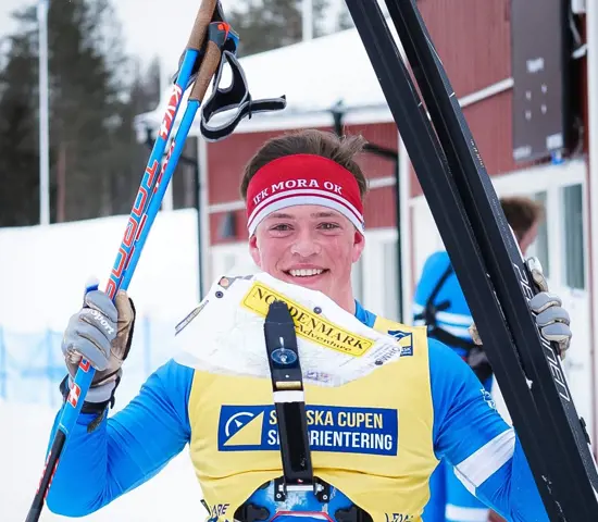 En leende Jonatan Ståhl lyfter skidor och stavar efter sitt SM-guld på medeldistans.