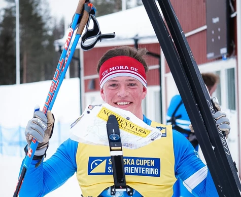 En leende Jonatan Ståhl lyfter skidor och stavar efter sitt SM-guld på medeldistans.