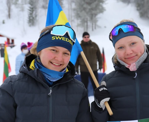 Två juniorer glada juniorer med svensk flagga under skidorienterings VM i Finland
