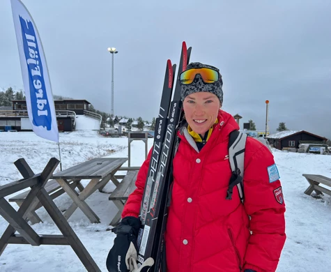 Tove Alexandersson med ett leende och två par skidor mot axeln på Idrefjäll.