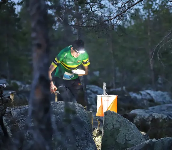 NTNUI-löpare stämplar vid en kontroll i mörkret på Tiomila i Skellefteå 2023.