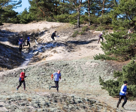 Orienterare springer kors och tvärs mellan sanddynorna i Åhus.