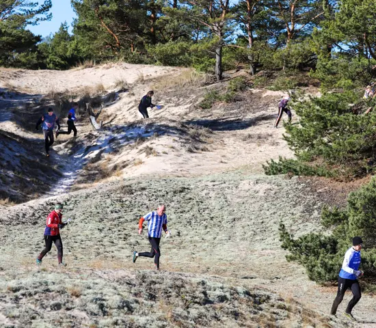 Orienterare springer kors och tvärs mellan sanddynorna i Åhus.