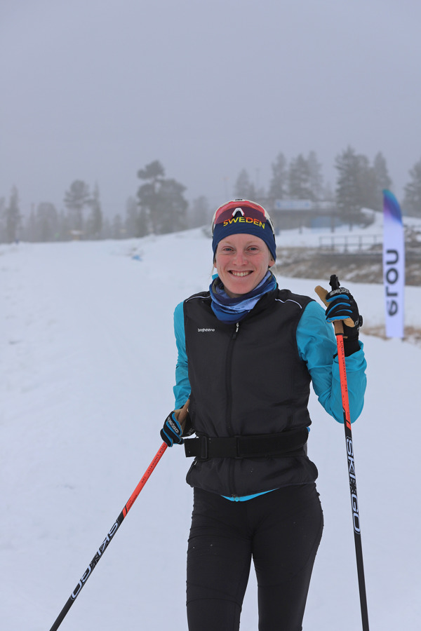 Linda Lindkvist med ett stort leende. I bakgrunden utlagd snö på Idrefjäll.