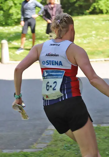 En tjej stämplar vid en kontroll intill en tegelvägg på sprint-SM-stafetten i Lund.