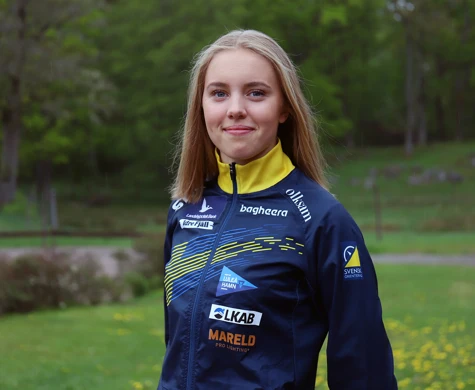 Hanna Lundberg med grön gräsmatta och skog bakom sig.