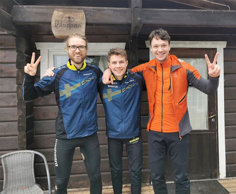 Gustav Bergman, Noel Braun och Nils van der Poel med glada miner utanför stuga.